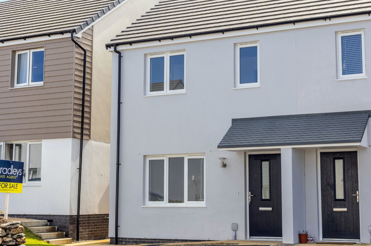 Image of a modern house in grey render, showcasing architectural details and landscaping.